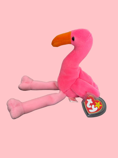Pink flamingo plush toy with a visible brand tag on a pink background