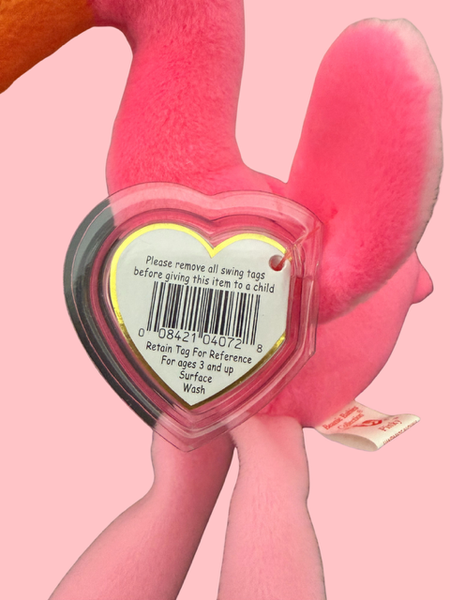 Pink plush toy with a heart-shaped tag on a pink background